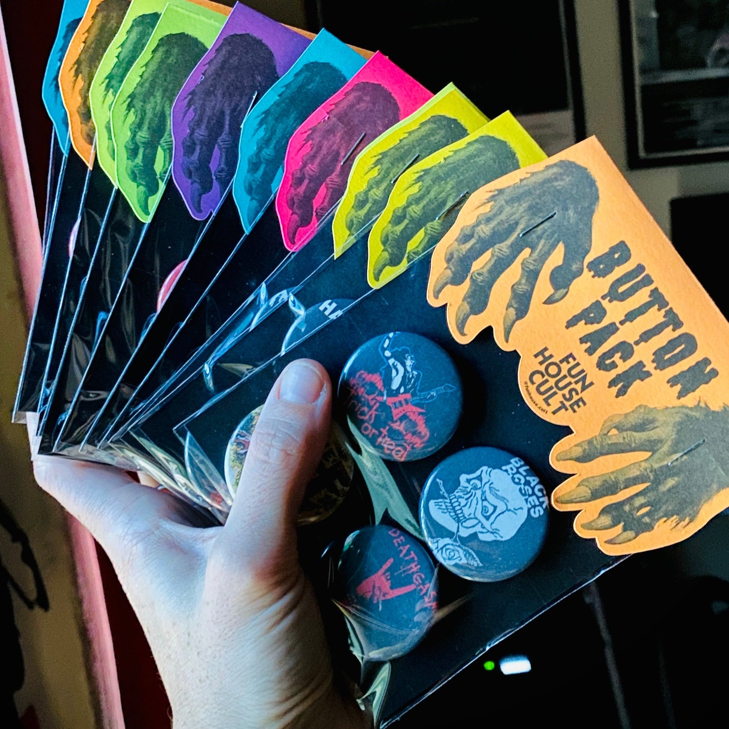 Hand holding a box of colorful button packs with visible branding.